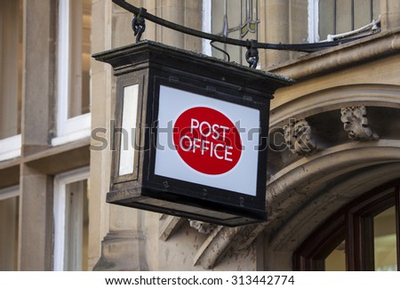 A Post Office sign hanging above a doorway.