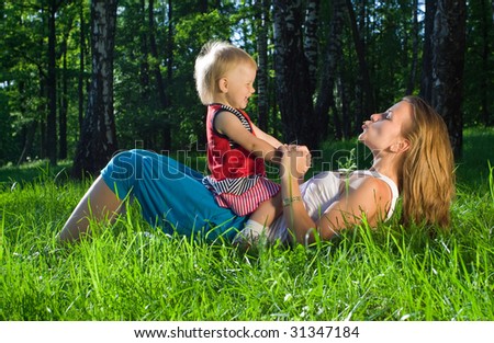 Young mother playing with  daughter on grass