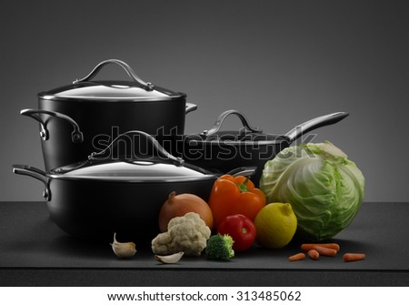 close up view of nice cookware set with some vegetables on grey color back Royalty-Free Stock Photo #313485062