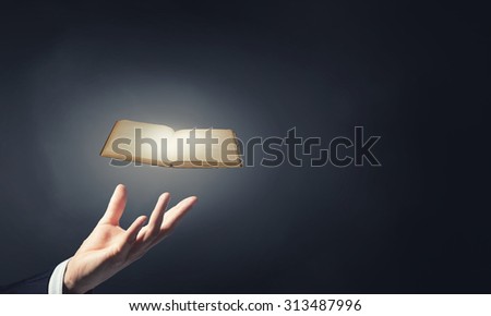 Close up of hand holding in palm glowing book