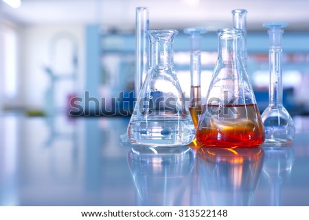 conical flask glassware with orange solution in chemical science laboratory in school or university technology background  Royalty-Free Stock Photo #313522148