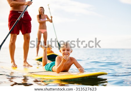 Family Having Fun Stand Up Paddling Together in the Ocean on Beautiful Sunny Morning Royalty-Free Stock Photo #313527623