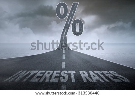 The words Interest Rates on a asphalt road and a percent sign at the top of the street, symbolizing the rising interest rates