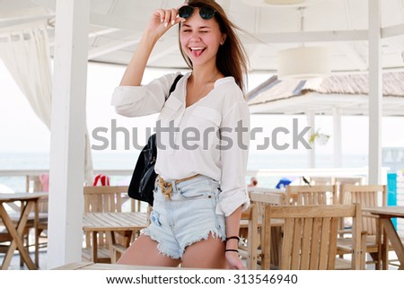 Outdoor summer closeup portrait of funny pretty young smiling girl having fun and going crazy showing tongue 