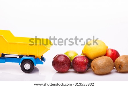 Citrus tropical fruits of yellow lemon red nectarine purple plum kiwi green lime near plastic lorry toy basket on studio white background copyspace, horizontal picture