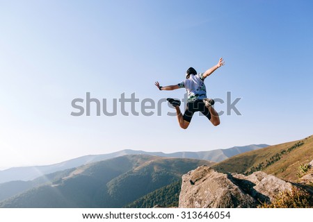 man jumps from the cliff in mountains Royalty-Free Stock Photo #313646054