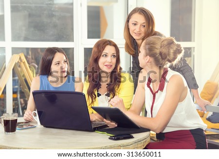 Working days in the women's team. Four young women - office staff. Discussion of joint work on the project. Female business. Women working in the office at the computer. Group of women. Toned image.