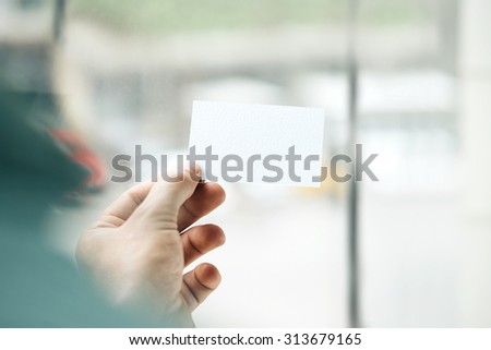 Male hand holding white business card on the window background