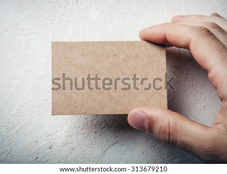 Closeup of male hand holding craft business card on concrete wal