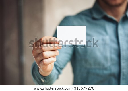 Man holding white business card on concrete wall background Royalty-Free Stock Photo #313679270