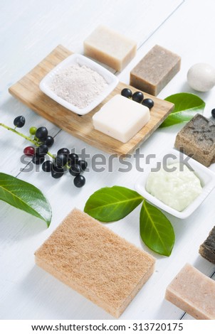 cosmetic clay, soaps, henna blocks, sponge and moisturizer on white wood table 