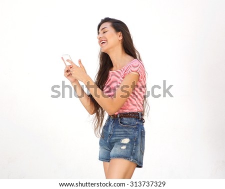 Side portrait of a smiling young woman walking and reading text message on cell phone