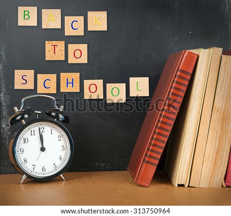 Back to school background with books, alarm clock and inscription