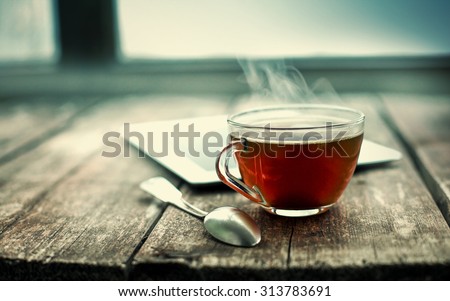 Hot tea cup on a frosty winter day window background Royalty-Free Stock Photo #313783691