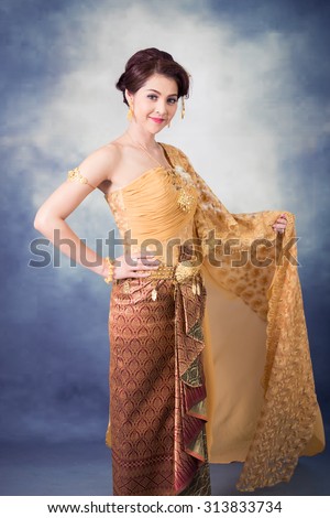 portrait beautiful thai woman in vintage thai traditional costume,gold color dress,smiling in studio light