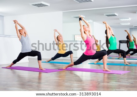 Four girls practicing yoga, Yoga - Virabhadrasana/Warrior pose Royalty-Free Stock Photo #313893014