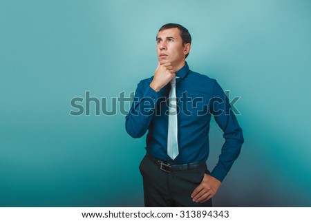 a man of European appearance thirty years thinking hand on chin on a gray  background