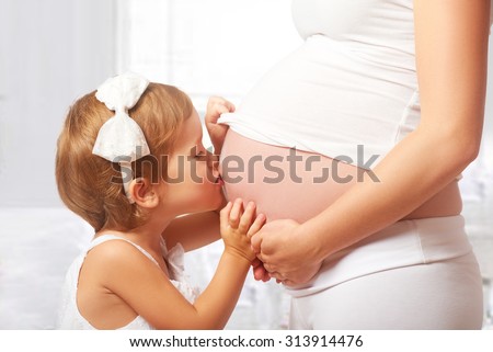 Happy family. Happy child kissing  belly of pregnant mother