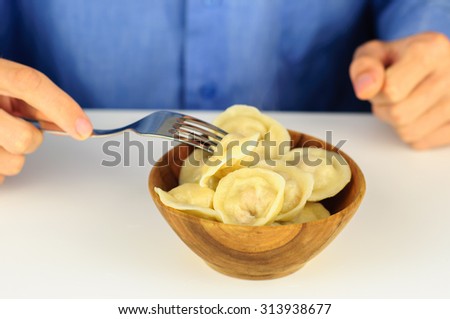 Young man in blue shirt eats dumplings with meat
