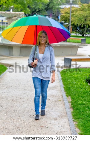 a young woman walks with a colorful umbrella in his hand walking in the rain.