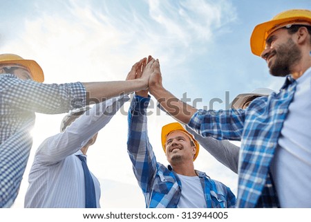 business, building, partnership, gesture and people concept - close up of smiling builders and architect in hardhats making high five outdoors Royalty-Free Stock Photo #313944005