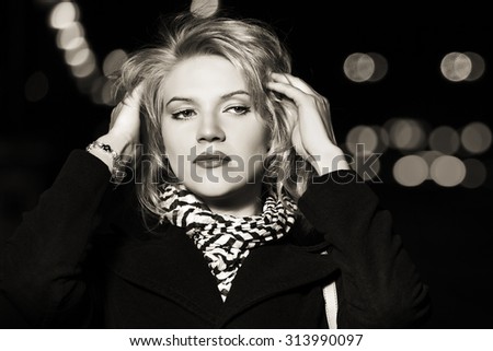 Young blond fashion woman walking on the night city street