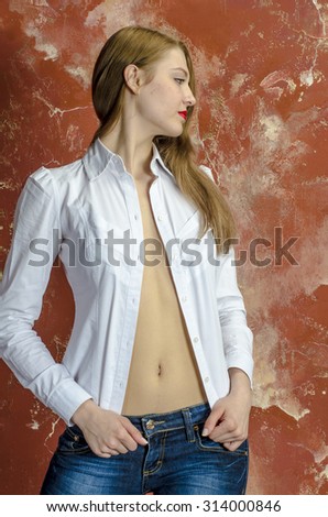 Young slim beautiful young blond woman with long legs and hair in shirt and jeans