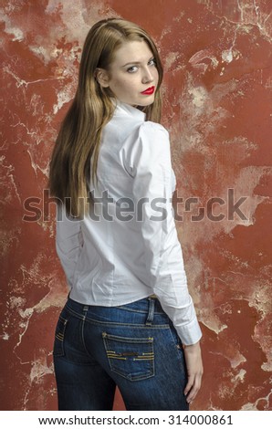 Young slim beautiful young blond woman with long legs and hair in shirt and jeans