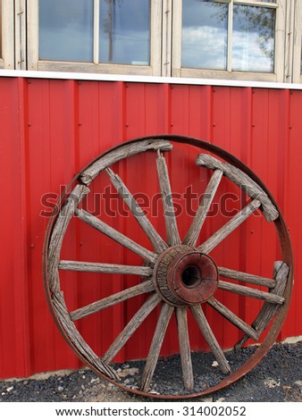 Old Wooden Wagon Wheel Leaning Against a Red Wall