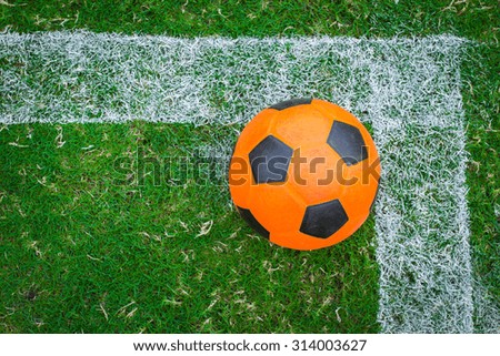 Soccer ball orange on green field.
