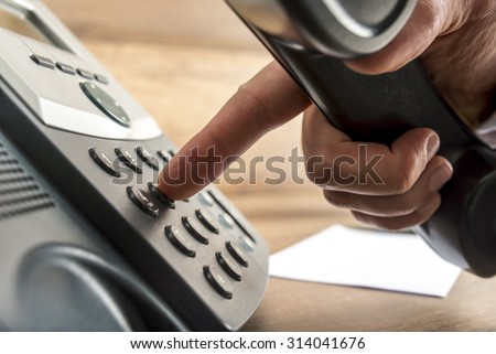 Closeup of male hand dialing a telephone number on black landline phone in a global communication concept. Royalty-Free Stock Photo #314041676