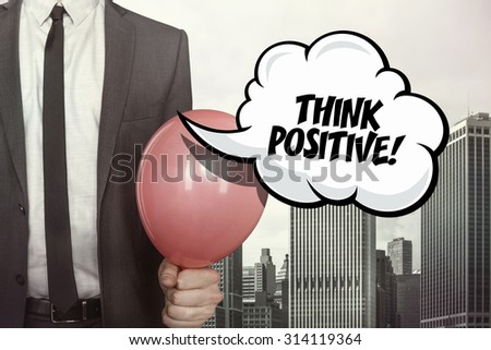 Think positive text on speech bubble with businessman holding balloon on cityscape background