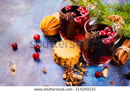 Hot xmas punch with spices and cranberry in glass cups. Xmas or new year concept. Xmas decorations, wooden background. Selective focus