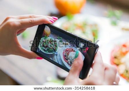 Girl photographs cooked meal using her smartphone