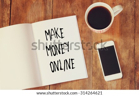 top view image of open note book with the phrase make money online, next to cup of coffee and smartphone.