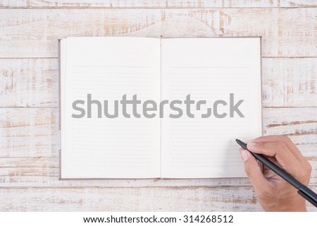 Man hand holding pencil and writing notebook  on wood table for text and background.copy space