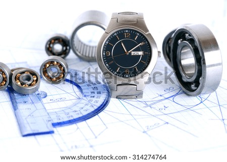 Engineering concept. Few ball bearings near ruler and wristwatch on graph paper background