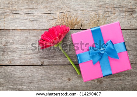 Purple gerbera flower and gift box on wooden table
