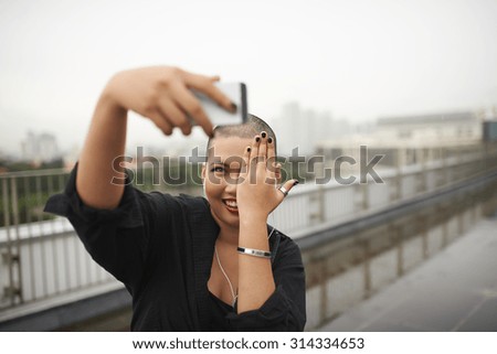 Pretty young woman coving her eye with a palm to take a creative selfie