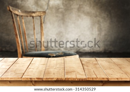 gray old worn wall in interior with retro chair and yellow wooden table 