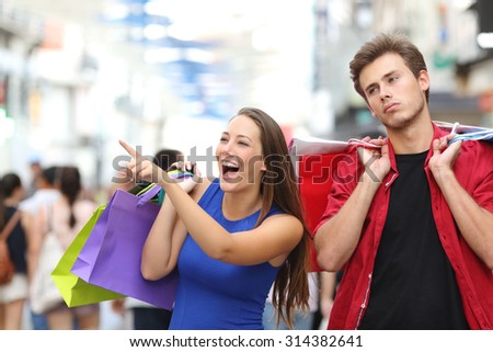 Bored man shopping with his girlfriend in a commercial street Royalty-Free Stock Photo #314382641
