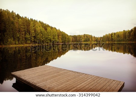 A nice view from the dock. A small pier is floating on a still water. Image has a vintage effect applied.