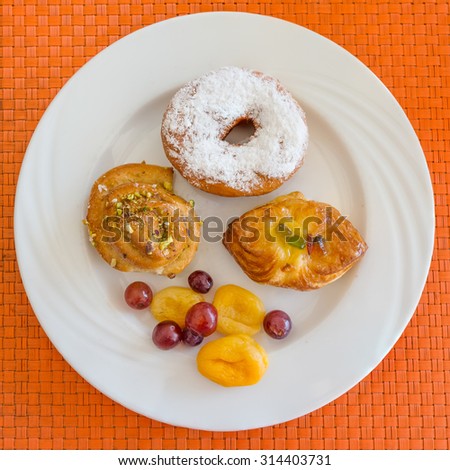 In the pictured three pastries served on a white plate with fruits as decoration.