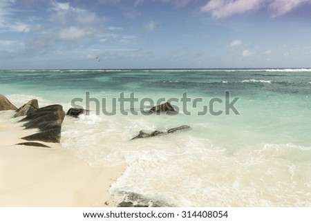 Paradise beach of Seychelles in la Digue island, Anse Source d'Argent. Boulders black granite rocks, turquoise water, white sand and blue sky.