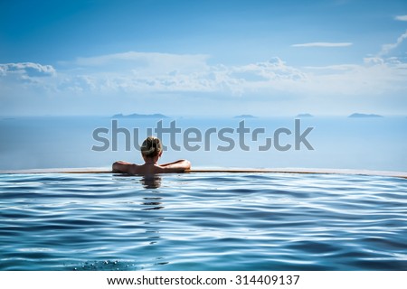 Woman relaxing in infinity swimming pool looking at view Royalty-Free Stock Photo #314409137