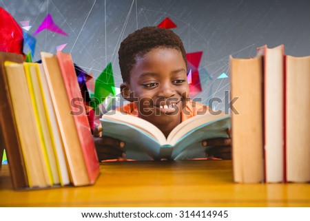 Cute boy reading book in library against geometric design