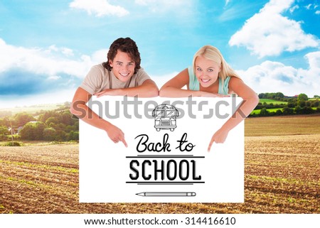 Man and cute woman pointing on a whiteboard against blue sky over fields