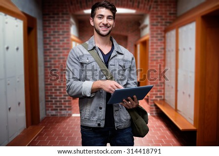 Student using tablet in library against brick walled corridor with tiled flooring in college