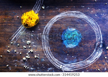 Sun, earth and moon hand drawing by chalk on vintage table.  Sun is a yellow flower.