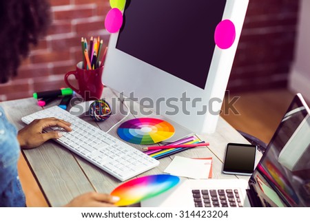 Female graphic designer working at desk against red brick background
